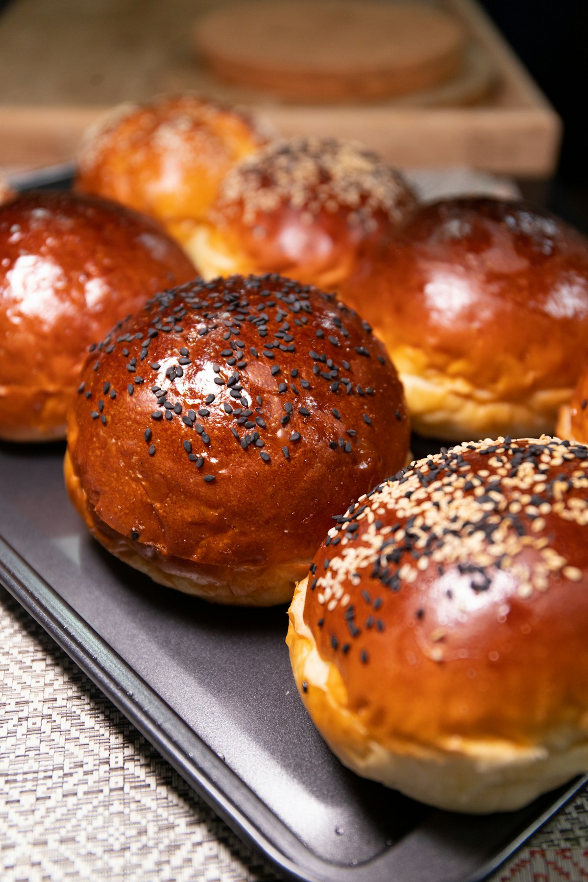 A tray of glossy sesame-topped brioche buns