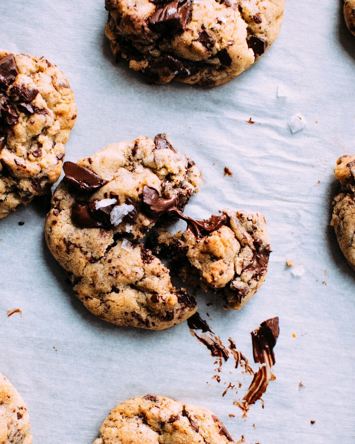 Broken chocolate chunk cookies surrounded by crumbs