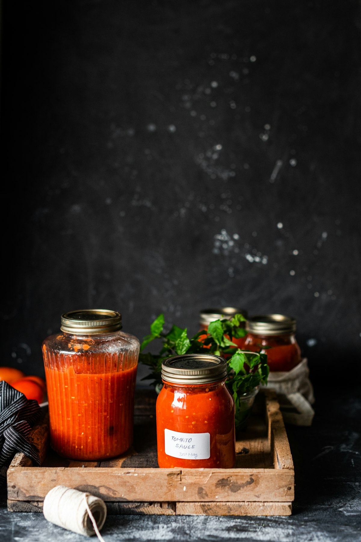 Glass jars of sauce and pesto on a dark bench