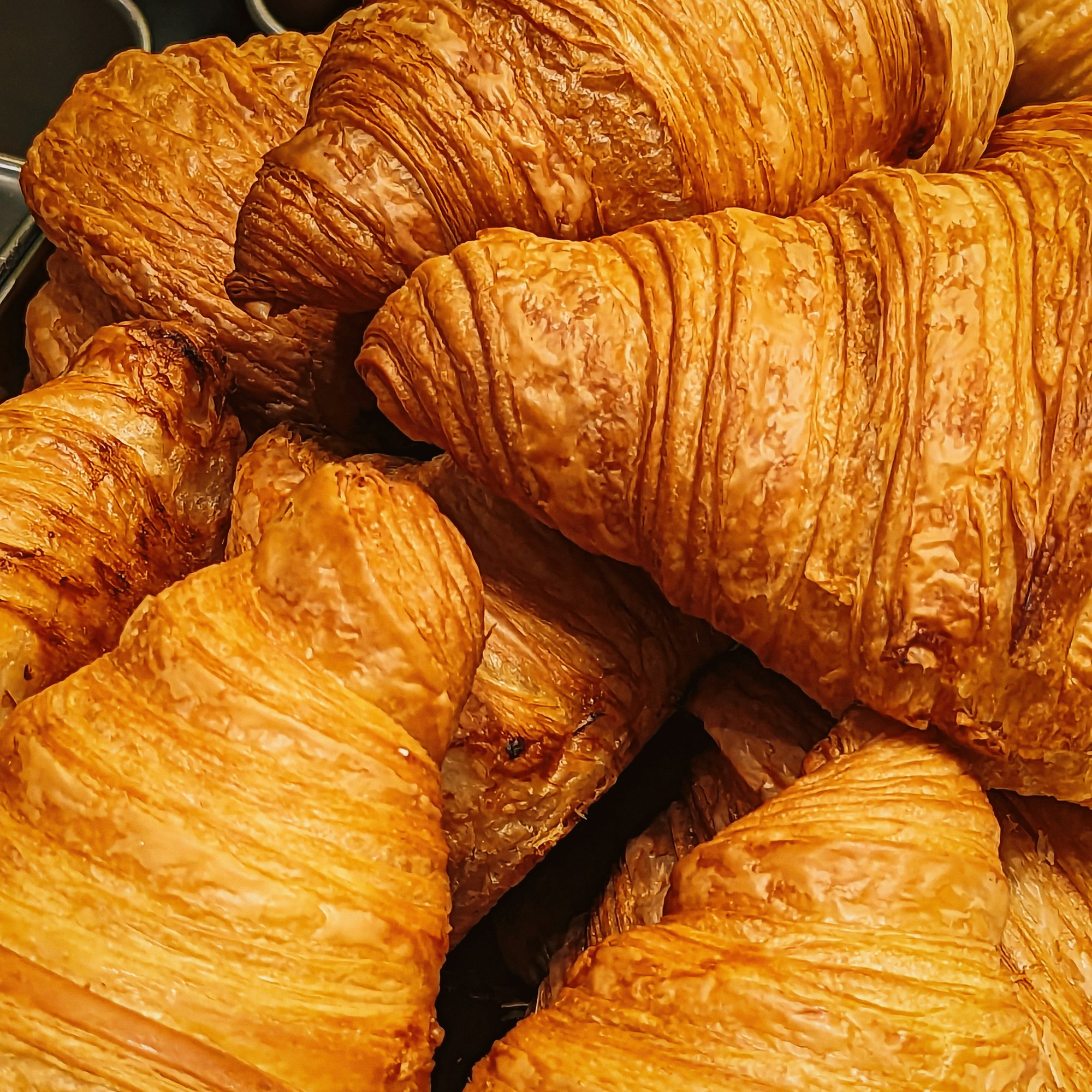A pile of freshly baked croissants, layers visible along the crust